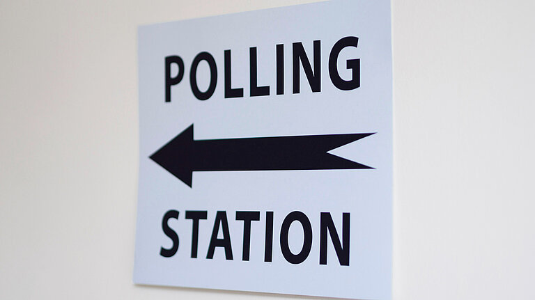 A sign with an arrow and the words "Polling Station"